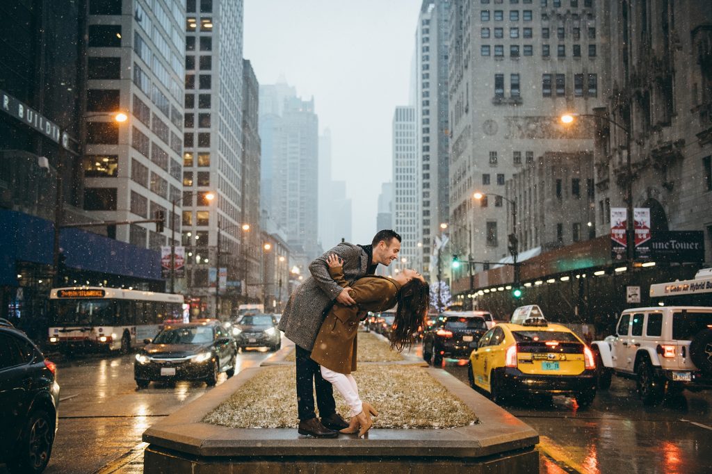 A smiling couple dances together in the rain in the streets of Chicago.