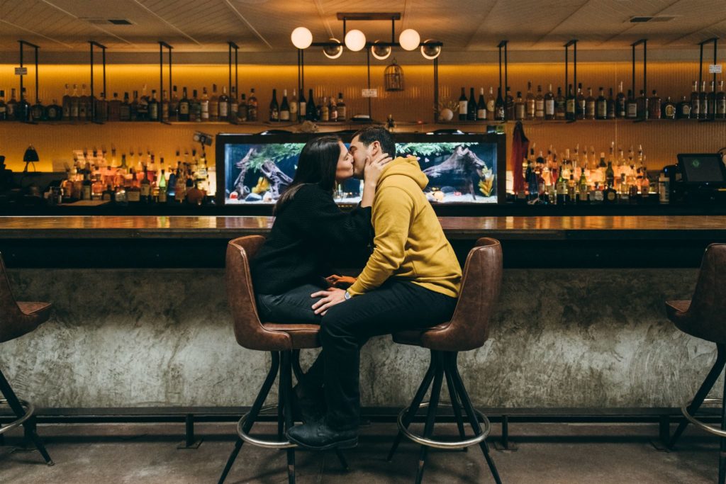 A couple kisses at their favorite bar during engagement photos in Chicago. 