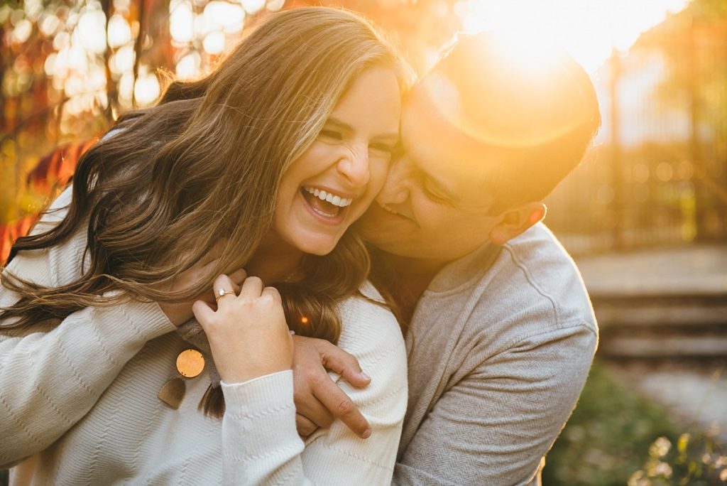 A couple hugs and smiles brightly during golden hour engagement photos in Chicago.
