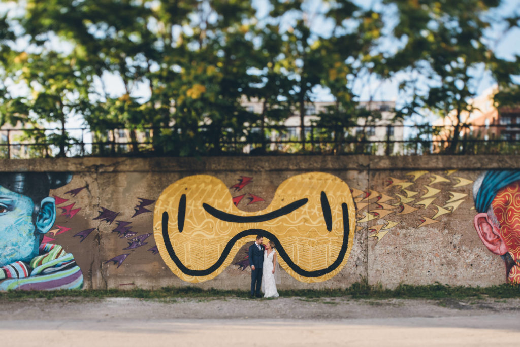 A bride and groom stand in front of the murals on 16th street in pilsen, one of the most popular chicago photo spots.
