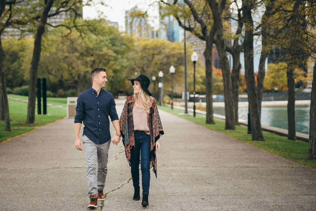 A couple walks hand-in-hand during an engagement photoshoot in Milton Lee Olive Park in Chicago.